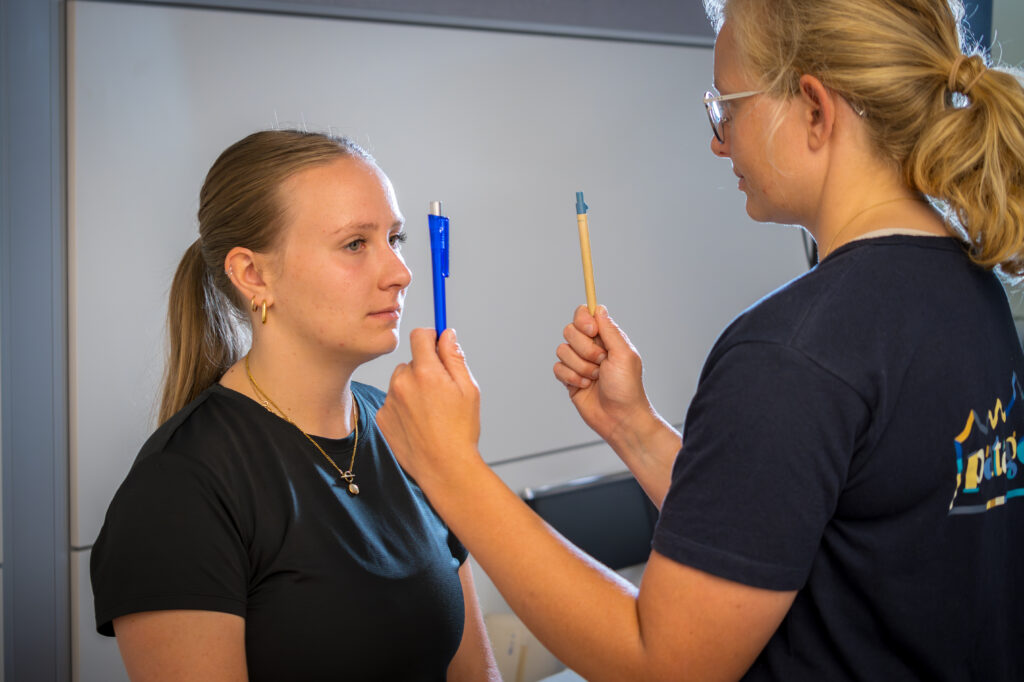 Spezialisierte Physiotherapeutin in Basel führt einen VOMS-Test mit horizontalen Sakkaden bei einer Patientin durch